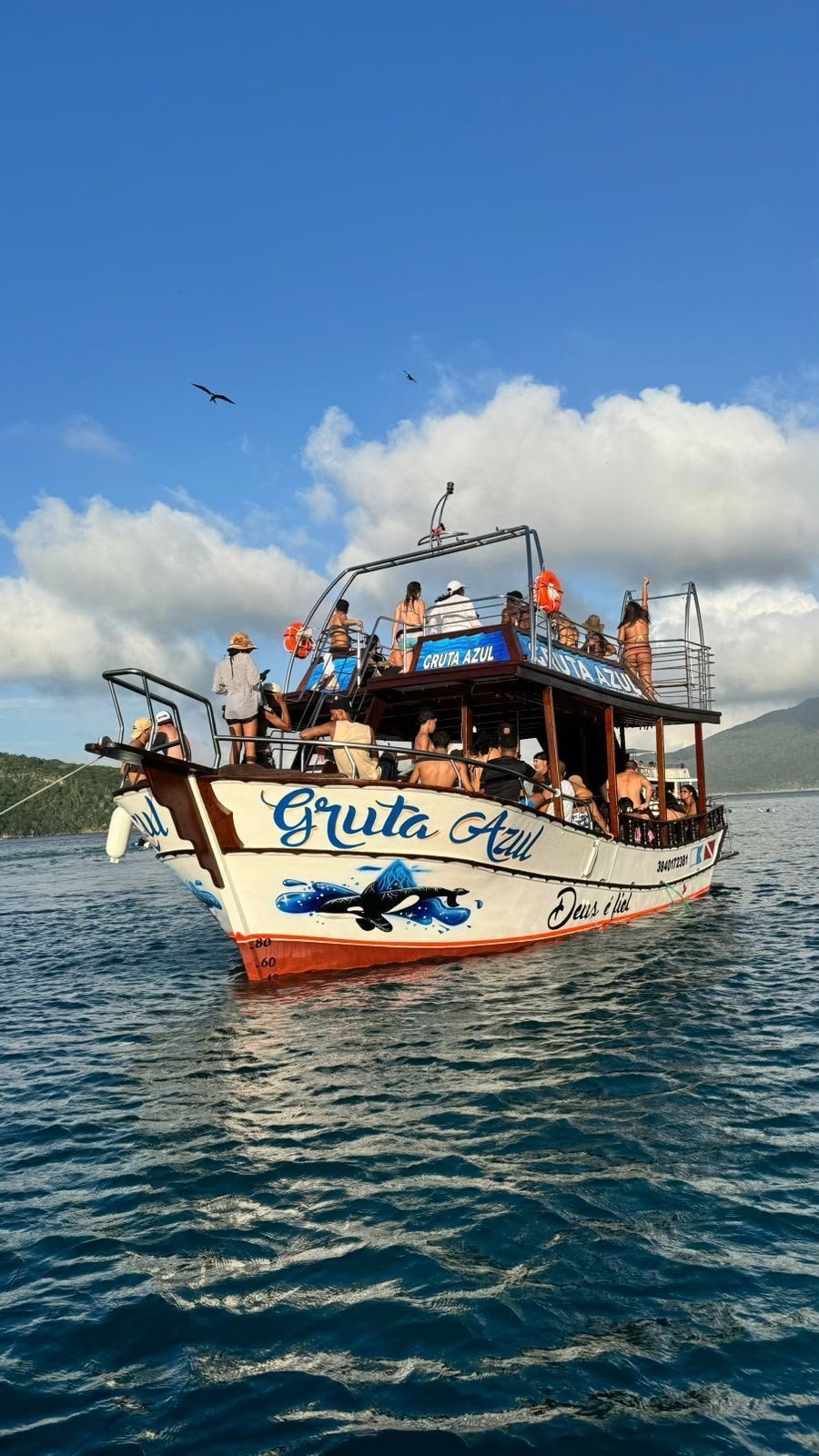 Embarcação Gruta Azul navegando com passageiros no mar de Arraial do Cabo